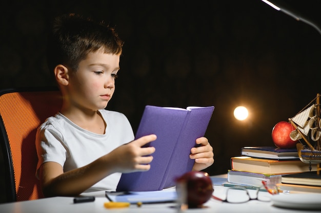 Menino fazendo lição de casa em casa à noite