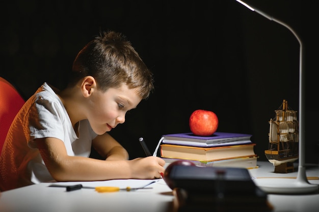 Menino fazendo lição de casa em casa à noite