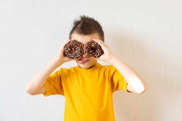 Menino fazendo óculos de rosquinhas de chocolate