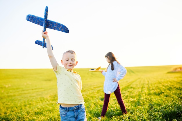 Menino fecha os olhos e sonha em voar Crianças alegres e felizes brincam no campo e se imaginam pilotos em um dia ensolarado de verão Crianças sonham em voar e aviação