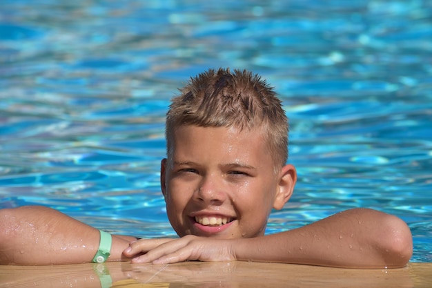 Menino feliz alegre nadar na piscina no verão lá fora. temporada de natação turística para crianças no mar
