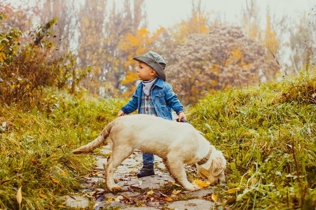 Menino feliz andando com seu cachorro golden retriever no parque