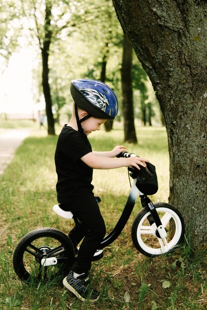 Menino feliz andando de bicicleta correndo no parque