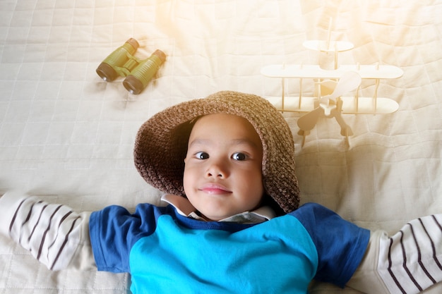 Menino feliz brincando com avião de brinquedo, pequeno garoto asiático goza de viagem, conceito de viagem e aventura