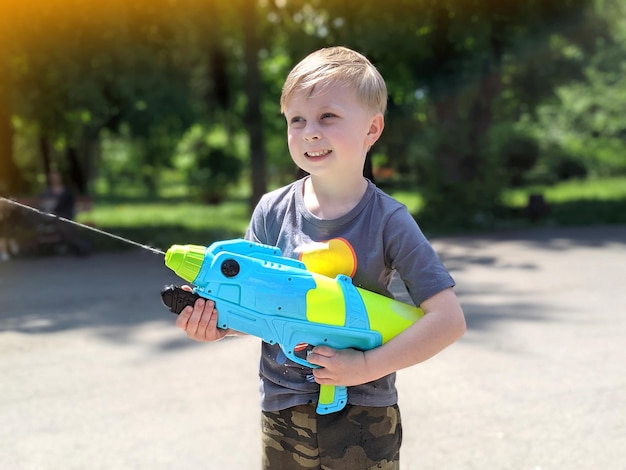 menino feliz brincando com pistolas de água lá fora