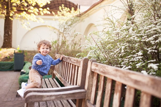 Menino feliz brincando e correndo no parque na primavera. Criança sorridente brincar no parque da cidade.