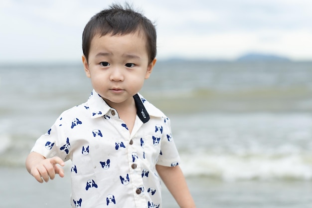 Foto menino feliz brincando na areia com praia de verão mar