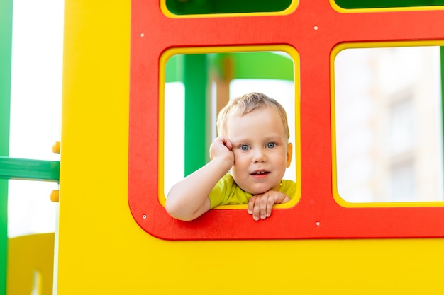 Menino feliz brincando no playground, menino olhando pela janela, estilo de vida infantil