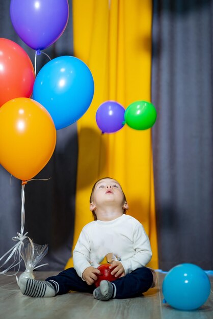 Menino feliz com balões coloridos Um menino está se divertindo com um monte de balões