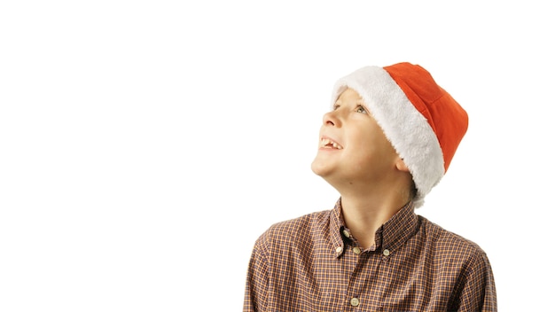 Menino feliz com chapéu de Papai Noel parece para o lado, isolado no fundo branco.