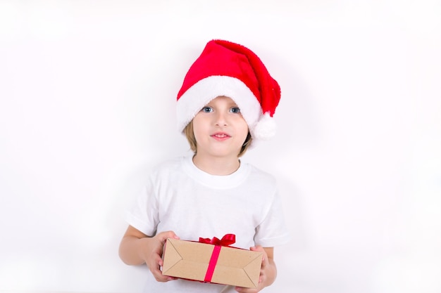 Foto menino feliz com chapéu de papai noel vermelho segurando o presente de natal na mão. conceito de natal.
