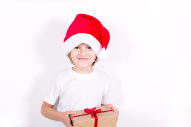 Menino feliz com chapéu de papai noel vermelho segurando o presente de natal na mão. conceito de natal.