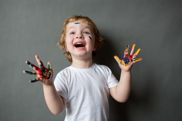 Menino feliz com mãos coloridas em cinza