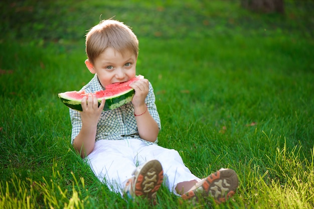 Menino feliz criança come melancia no verão