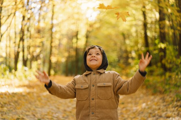 Menino feliz criança rindo e brincando no dia de outono criança brincar com folhas