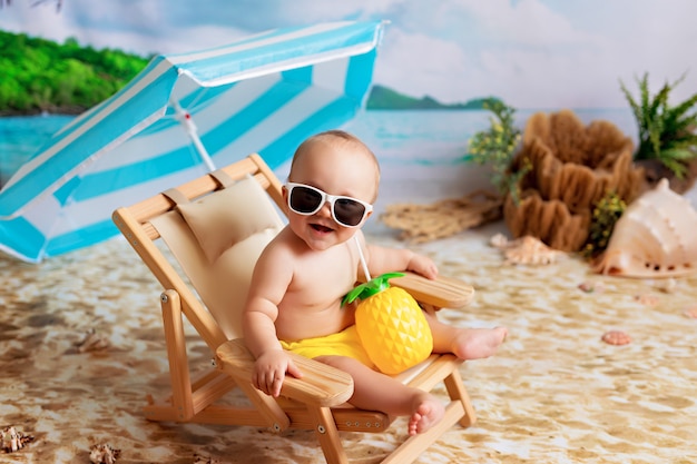 Menino feliz de óculos deitado em uma espreguiçadeira, tomando banho de sol em uma praia à beira-mar e bebendo suco