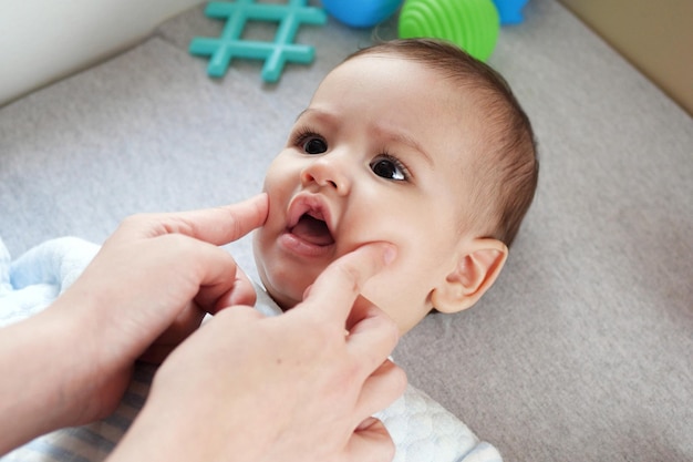 Foto menino feliz deitado na mão da mãe pressionando suas bochechas