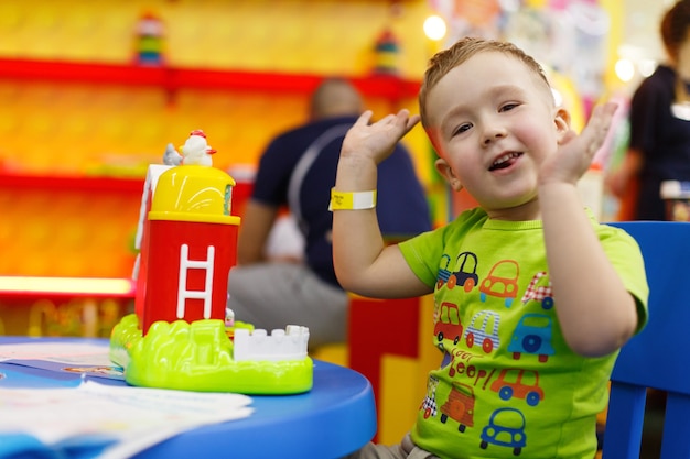 Foto menino feliz e sorridente brincando com um brinquedo colorido no quarto das crianças, criança bonita no jardim de infância