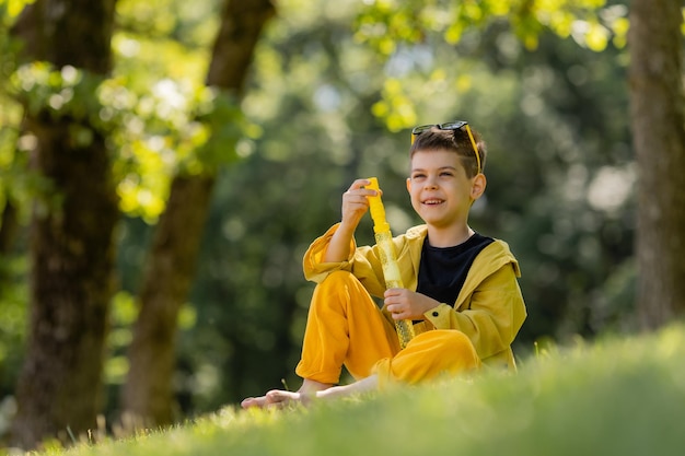 menino feliz em óculos de sol pega bolhas de sabão no parque no verão