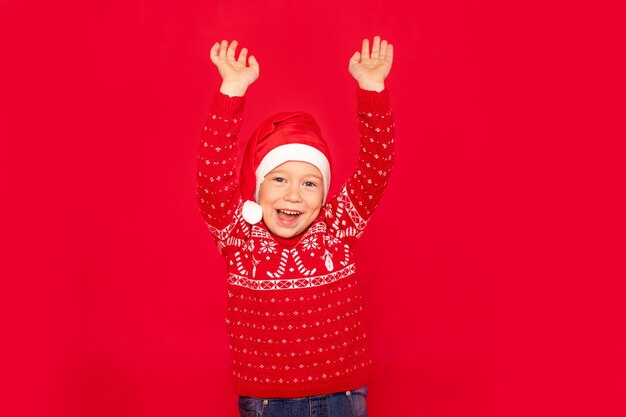 Menino feliz em um fundo vermelho, criança com as mãos para cima