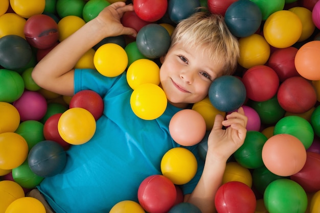 Menino feliz jogando na piscina da bola