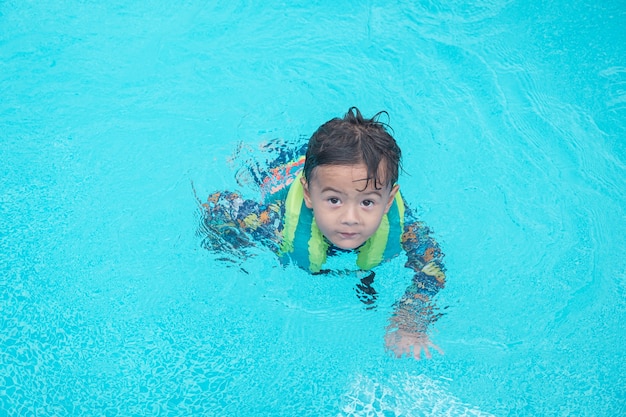 Menino feliz nadar e mergulhar na água, peito de criança com diversão na piscina. estilo de vida ativo e saudável, esportes aquáticos e aulas com os pais nas férias de verão com a criança.