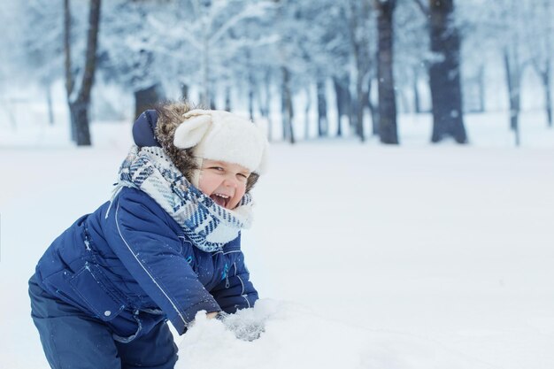 Menino feliz no parque de inverno nevado