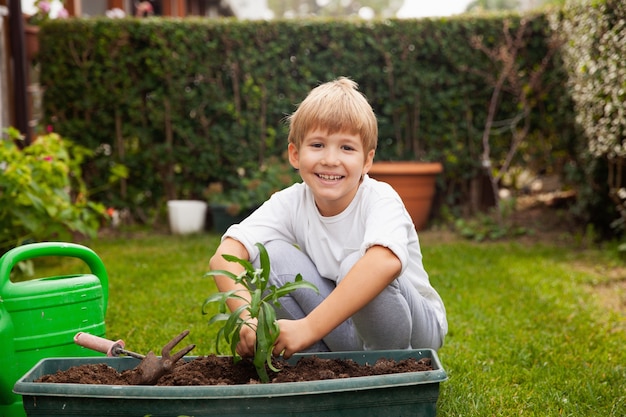 Menino feliz plantando e cultivando flores