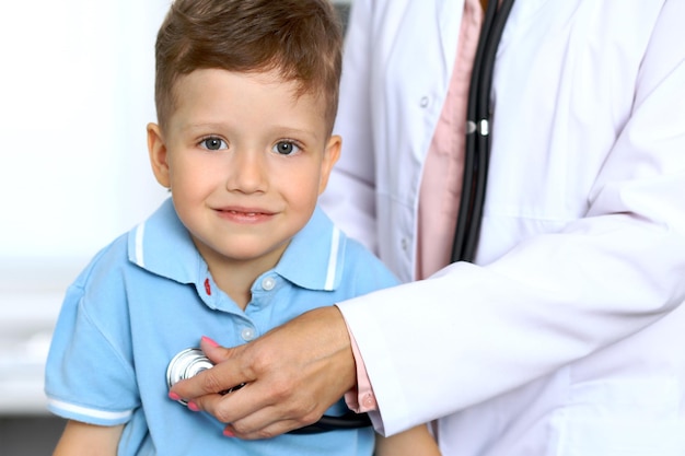 Menino feliz se divertindo enquanto está sendo examinado pelo médico com estetoscópio