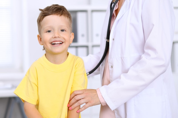 Menino feliz se divertindo enquanto está sendo examinado pelo médico pelo estetoscópio Seguro de saúde e conceito de ajuda