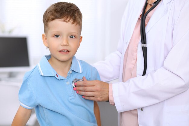 Menino feliz se divertindo enquanto está sendo examinado pelo médico pelo estetoscópio Seguro de saúde e conceito de ajuda