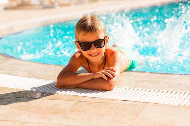 Foto menino feliz se divertindo na piscina do resort