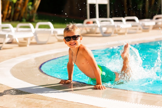 Foto menino feliz se divertindo na piscina do resort