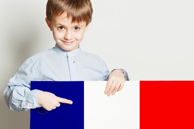 Menino feliz segurando a bandeira da bandeira de Franch em fundo branco vazio