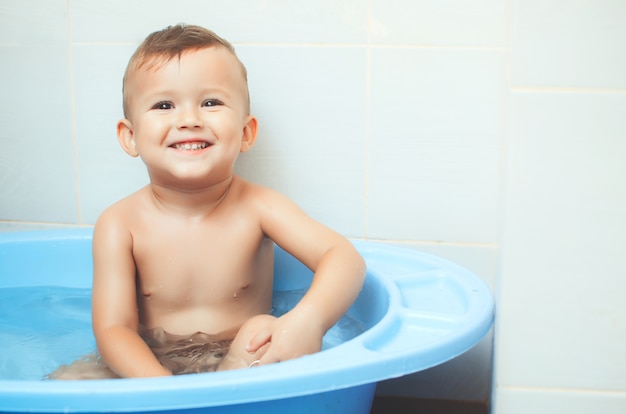 Menino feliz sentado na banheira, olhando e sorrindo
