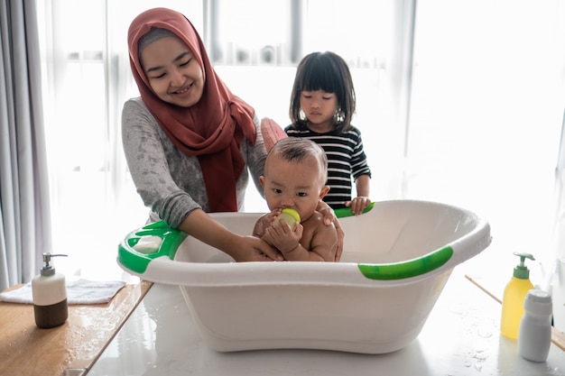 Menino feliz tomando banho com mãe e irmã