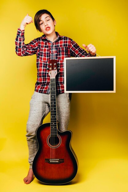 Foto menino fica com guitarra e placa preta com espaço de cópia