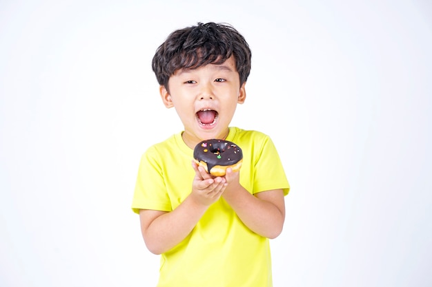 Menino fofo asiático comendo rosquinha grande