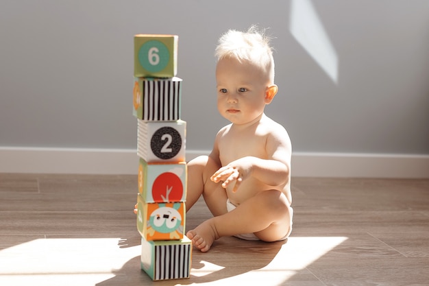 Menino fofo brincando em casa com cubos coloridos