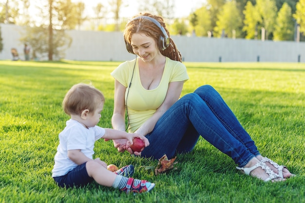 Menino fofo com a mãe brincando com maçãs