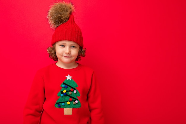 Menino fofo com um suéter de Natal e um chapéu