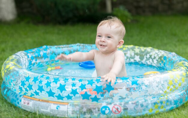 Menino fofo de 9 meses se divertindo em uma piscina inflável