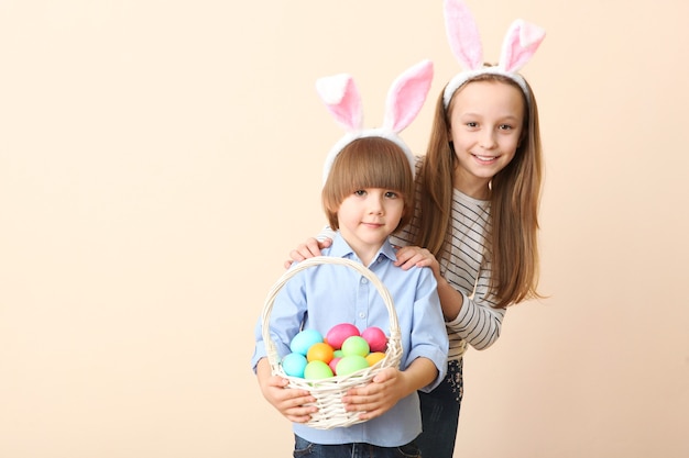 Menino fofo e menina com orelhas de coelho e uma cesta de Páscoa