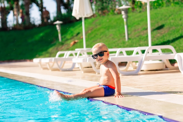 Menino fofo feliz se divertindo na piscina do resort de férias