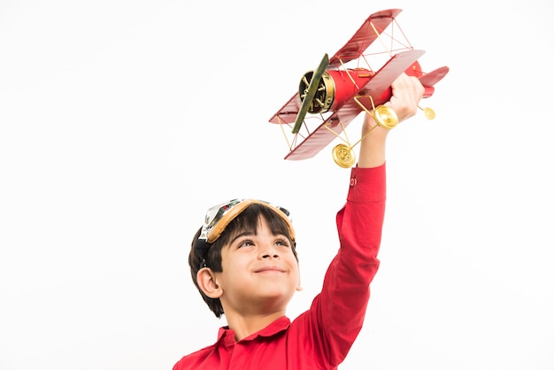 Menino fofo indiano ou asiático com avião de brinquedo sobre fundo branco