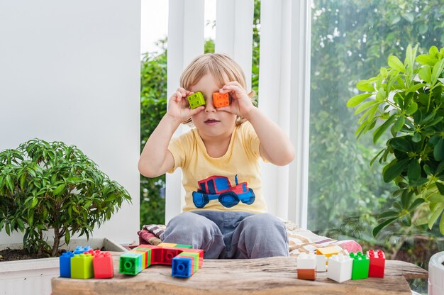 Foto menino garoto bonitinho com brincar com muitos blocos de plástico coloridos no interior