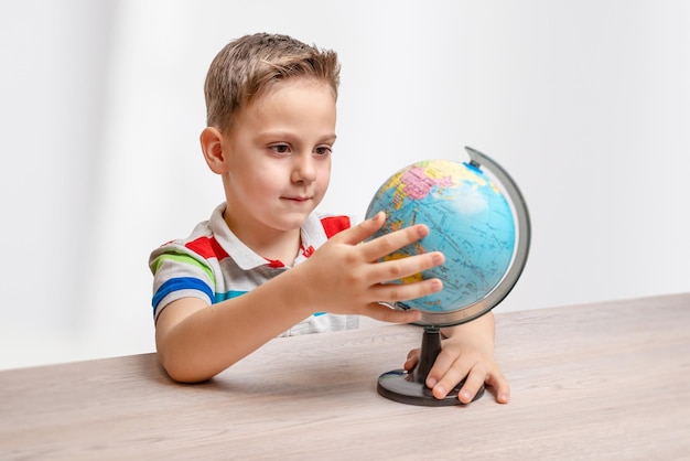 Menino gira o globo na mesa Boncept de aprender geografia e educação infantil