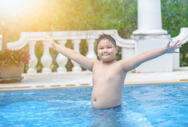 Menino gordo obeso feliz na piscina,