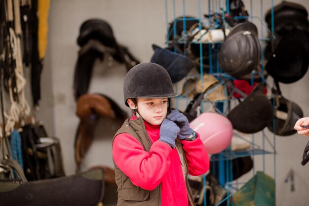 Menino hispânico usa capacete protetor de equitação para segurança no esporte de equitação Escola de equitação