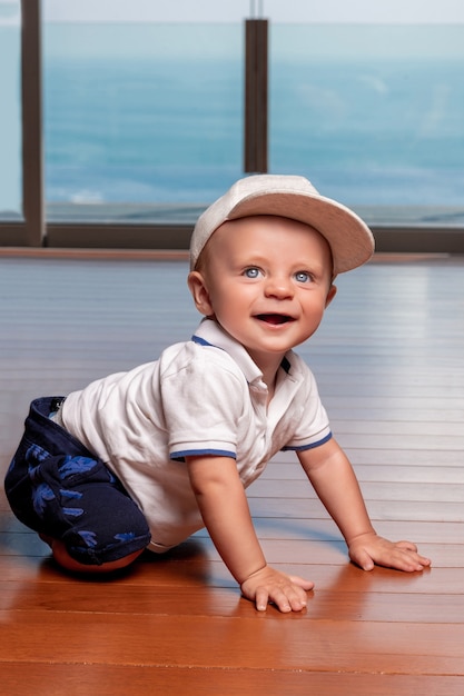 Menino infantil feliz usando um boné da moda com grandes olhos azuis, sorrindo e fazendo poses para a câmera